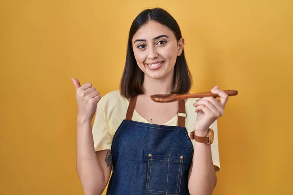 Hispanic Girl Eating Healthy Wooden Spoon Pointing Back Hand Thumbs — Zdjęcie stockowe
