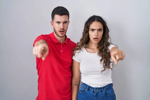 Young Hispanic Couple Standing Isolated Background Pointing Displeased Frustrated Camera — Zdjęcie stockowe