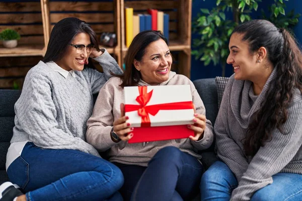 Three woman surprise with gift sitting on sofa at home