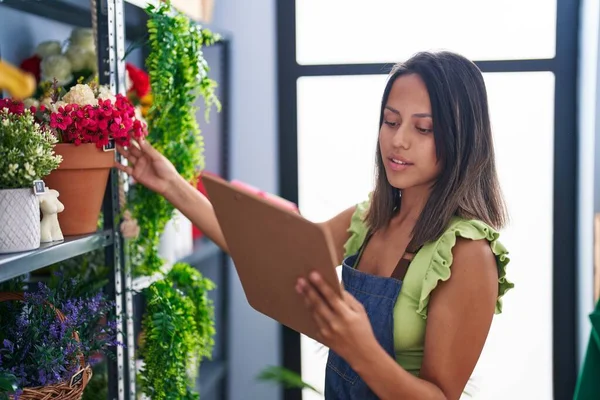 Young Hispanic Woman Florist Reading Document Organize Shelving Florist Store —  Fotos de Stock