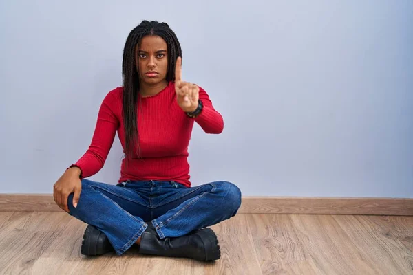 Young African American Braids Sitting Floor Home Pointing Finger Angry — Foto Stock