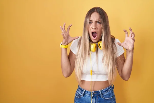 Young Blonde Woman Standing Yellow Background Wearing Headphones Crazy Mad — Stock Photo, Image