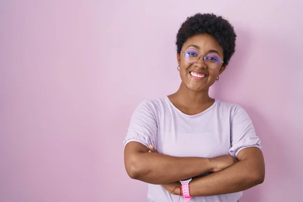 年轻的非洲裔美国女人站在粉红的背景上开心地微笑着 双臂交叉地看着相机 积极的人 — 图库照片