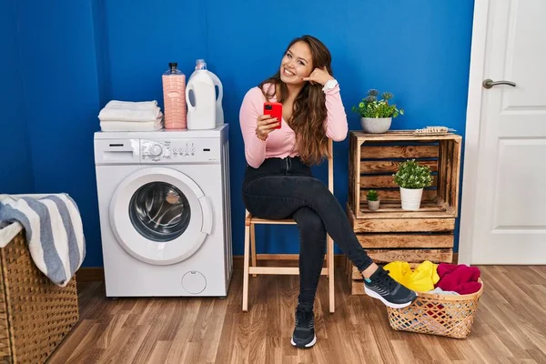 Young Hispanic Woman Sitting Waiting Laundry Using Smartphone Smiling Doing — Foto de Stock