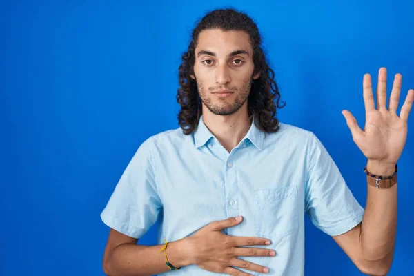 Jovem Hispânico Sobre Fundo Azul Jurando Com Mão Peito Palma — Fotografia de Stock