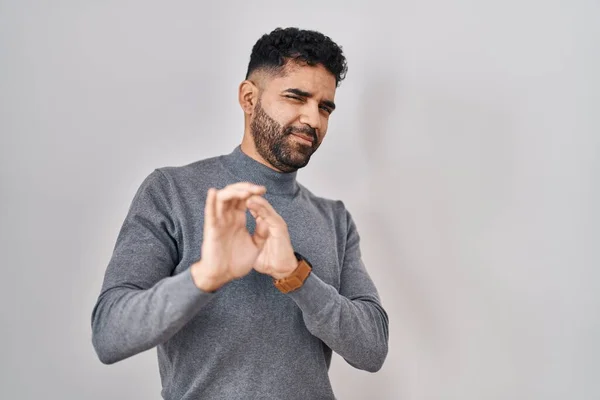 Hispanic man with beard standing over white background disgusted expression, displeased and fearful doing disgust face because aversion reaction.
