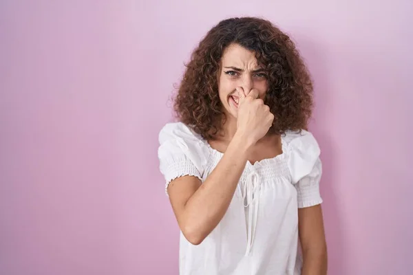 Hispanic Woman Curly Hair Standing Pink Background Smelling Something Stinky — Stockfoto