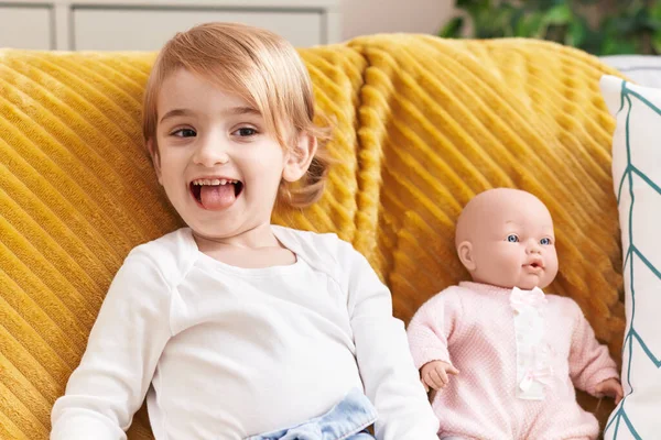 Sevimli Beyaz Kız Evinde Oyuncak Bebekle Kanepede Oturarak Gülümsüyor — Stok fotoğraf