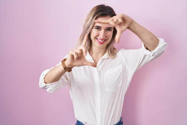Young Beautiful Woman Standing Pink Background Smiling Making Frame Hands — Stock Photo, Image