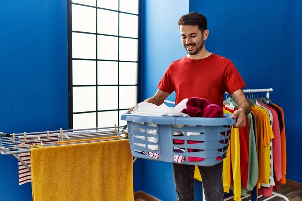 Mladý Hispánec Muž Usměvavý Jistý Držení Koš Oblečením Prádelně — Stock fotografie