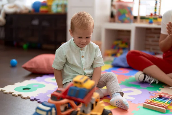 Stock image Adorable toddler playing with car toy sitting on floor at kindergarten