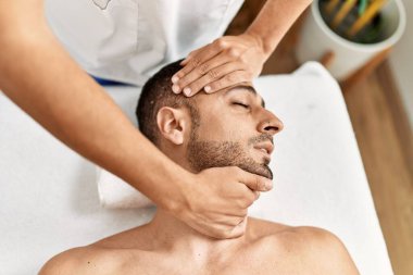 İki İspanyol erkek terapist ve hasta güzellik merkezinde yüz masajı yapıyorlar.