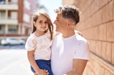 Father and daughter smiling confident hugging each other at street