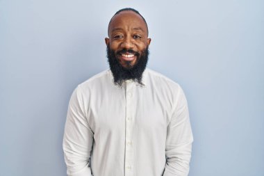 African american man standing over blue background with a happy and cool smile on face. lucky person. 