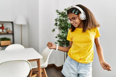 Afro-Amerikalı kız gülümseyerek evde dans ediyor.