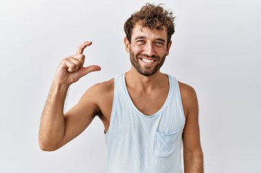 İzole edilmiş arka planda duran yakışıklı genç adam gülümsüyor ve el hareketleriyle hareket ediyor parmaklarıyla işaret yapıyor ve kameraya bakıyor. Ölçü kavramı. 