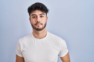 Beyaz arka planda duran sakallı İspanyol adam yüzünde ciddi bir ifadeyle rahatlamış. Basit ve doğal bir şekilde kameraya bakıyorsun.. 