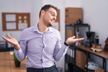 Ofisteki genç İspanyol adam gülümseyerek iki elini de açık tutuyor. Karşılaştırma ve reklam karşılaştırması yapıyor ve dengeyi sağlıyor. 