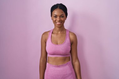 African american woman with braids wearing sportswear over pink background with a happy and cool smile on face. lucky person. 