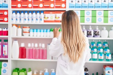 Genç sarışın eczacı eczanenin arkasında duruyor.