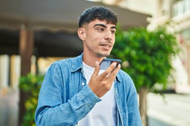 Genç İspanyol adam gülümsüyor. Kendine güveniyor. Sokakta akıllı telefondan konuşuyor.