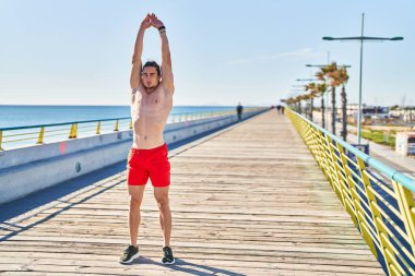 Young man stretching arms at seaside