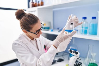 Laboratuvarda sıvıyı ölçen genç kadın bilim adamı.