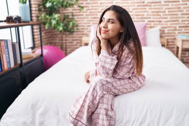 Young beautiful arab woman smiling confident sitting on bed at bedroom