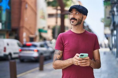 Sokakta akıllı telefon kullanan, kendine güvenen genç bir İspanyol.