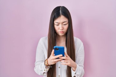 Akıllı telefondan mesaj yazan Çinli genç bir kadın bunalımlı ve sıkıntılı, sinirli ve korkmuş bir şekilde ağlıyor. hüzünlü ifade. 