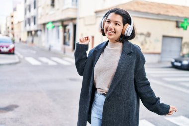 Sokak ortasında müzik dinleyen ve dans eden genç bir kadın.