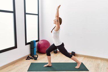 Spor merkezinde yoga eğitimi alırken gülümseyen beyaz bir kadın.