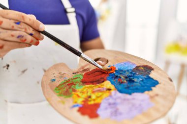 Genç İspanyol adam sanat stüdyosunda renkleri karıştırıyor.