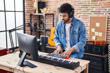 Genç Arap müzisyen müzik stüdyosunda piyano klavyesi çalıyor.