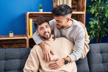 Young couple hugging each other sitting on sofa at home