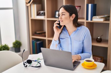 Evde çalışan akıllı telefondan konuşan genç bir kadın.