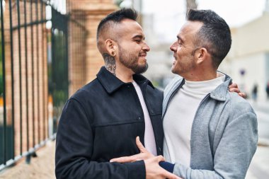 Two men couple smiling confident hugging each other at street