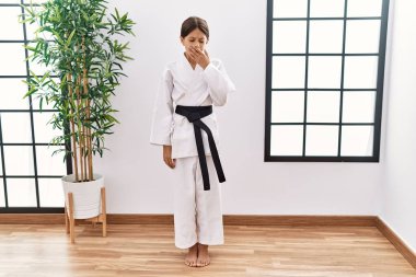Karate kimonosu ve siyah kuşak giyen genç İspanyol kız ağzıyla ağzını kapatmaktan sıkılmış. Huzursuz ve uykulu.. 