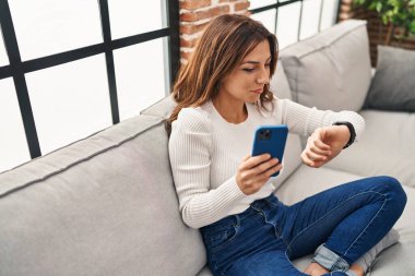 Genç İspanyol kadın evde akıllı telefon kullanıyor.