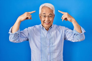 İspanyol kıdemli gözlüklü, gülümseyen, iki eliyle başını gösteren, harika bir fikir ya da düşünce, iyi bir hafıza 