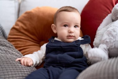 Sevimli çocuk evinde oyuncak bir tavşanla kanepede oturuyor.