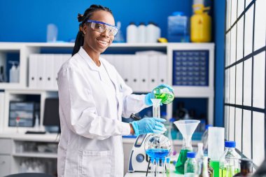 Laboratuvarda test tüpüne sıvı döken Afrikalı Amerikalı kadın bilim adamı.