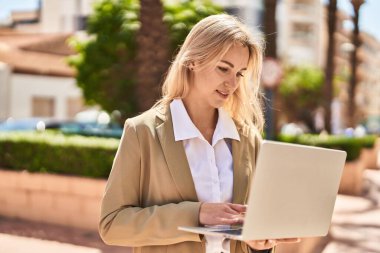 Young blonde woman executive smiling confident using laptop at park