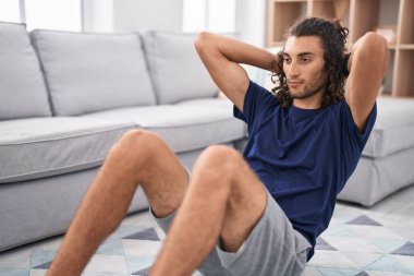 Young hispanic man training abs exercise at home