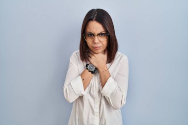 Young hispanic woman standing over white background shouting suffocate because painful strangle. health problem. asphyxiate and suicide concept. 