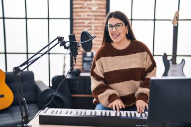 Genç İspanyol kadın müzisyen müzik stüdyosunda piyano klavyesi çalıyor.