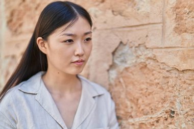 Çinli kadın sokakta rahat bir ifadeyle yan tarafa bakıyor.