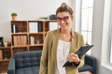 Young woman working at consultation office winking looking at the camera with sexy expression, cheerful and happy face. 