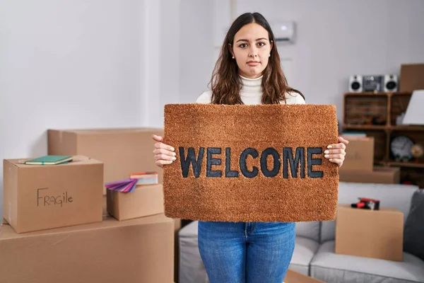 Young Hispanic Woman Holding Welcome Doormat New Home Relaxed Serious — Stockfoto