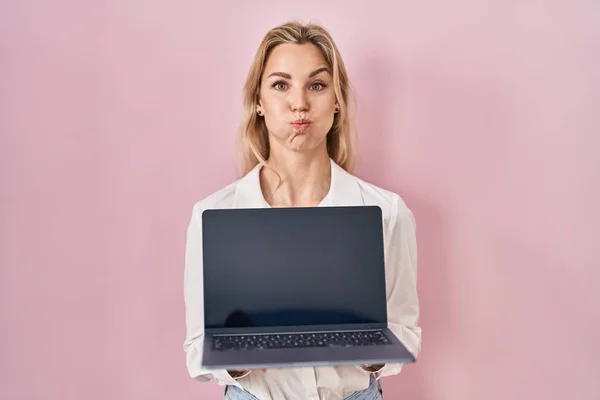 Young Caucasian Woman Holding Laptop Showing Screen Puffing Cheeks Funny — 图库照片